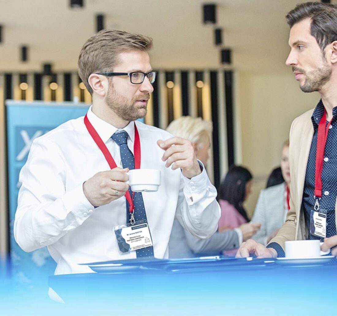 discussion between two men at a trade show wearing their event badge around the neck